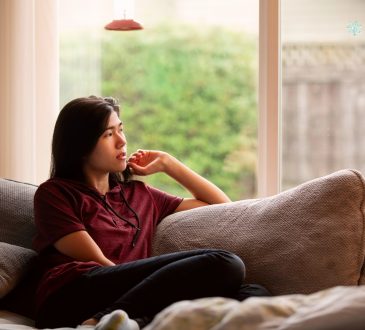 teen sitting on couch looking out window