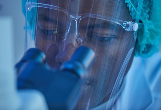 close up of man looking through microscope