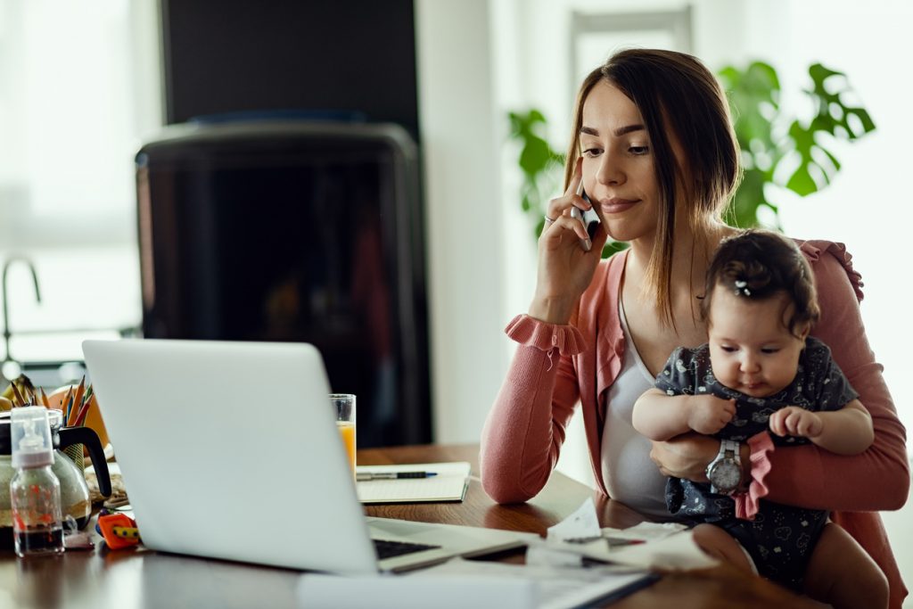 woman holding baby while working at home