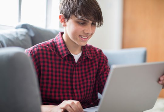 Teenage Boy Working On Laptop At Home