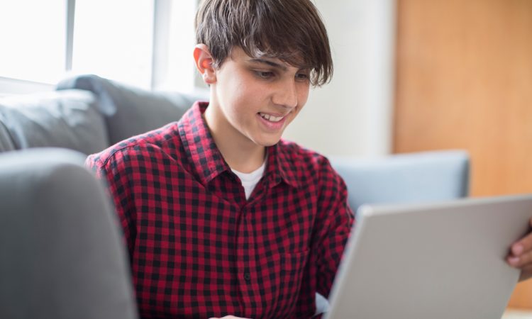 Teenage Boy Working On Laptop At Home