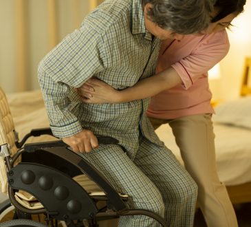 care worker helping elderly person out of wheelchair
