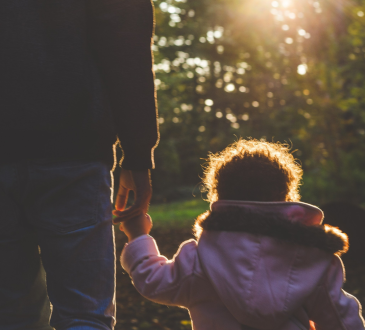 Parent and child holding hands walking outdoors