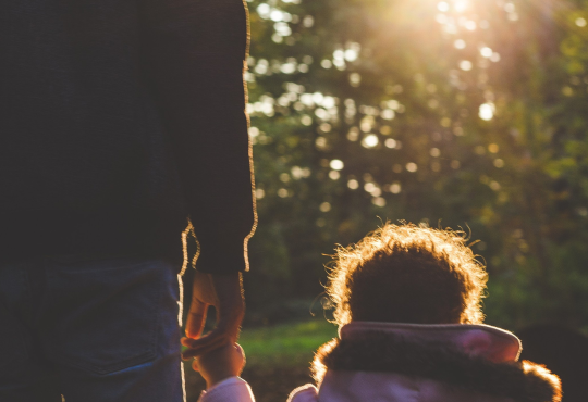 Parent and child holding hands walking outdoors