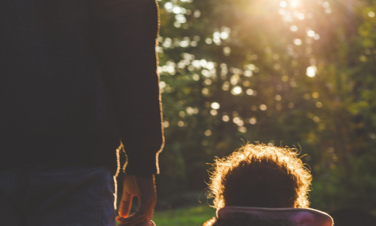 Parent and child holding hands walking outdoors