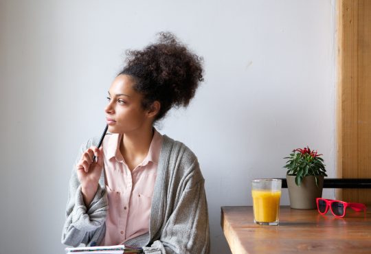 Portrait of a young woman sitting at home with pen and paper