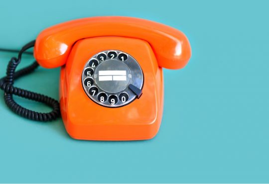 orange rotary phone on blue background