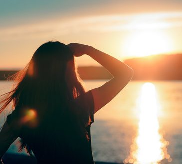 woman watching sun set over water