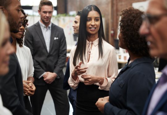 Business Team Standing Having Informal Meeting In Modern Office