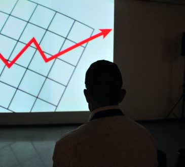 man silhouetted in front of screen showing chart