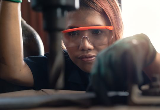 young woman using drill press