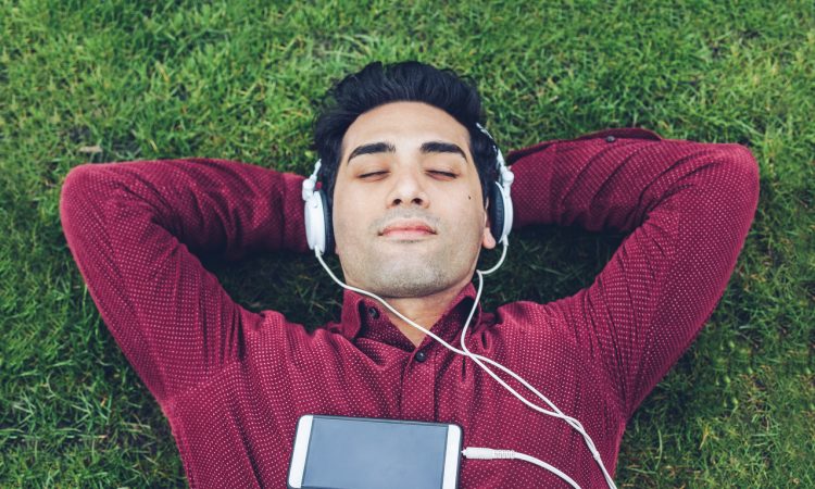 Young man relaxing in the park and listening music