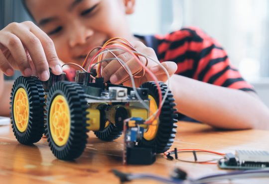 Concentrated boy creating robot at lab.