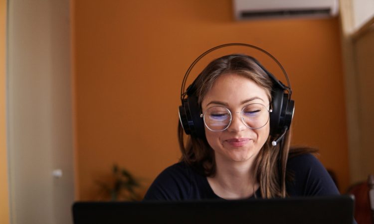 woman wearing headphones working on laptop