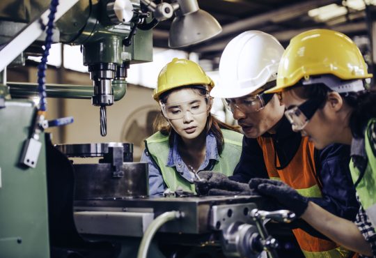 technician manager showing case study of factory machine to two engineer trainees