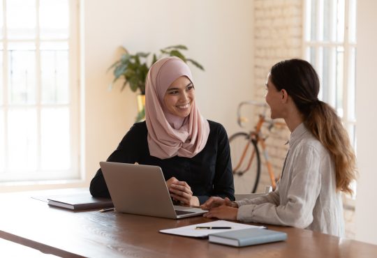 two women talking at table in office