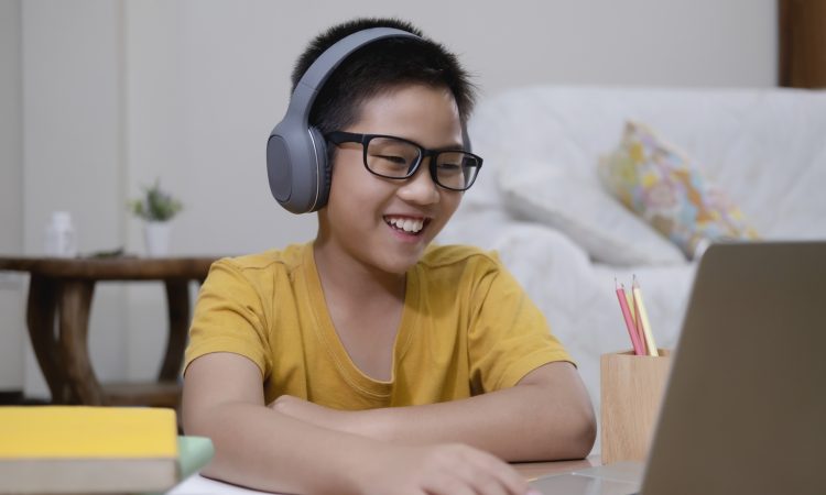 Cheerfully boy excited using computer online learning schoolwork.