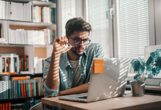 male student looking at laptop in library