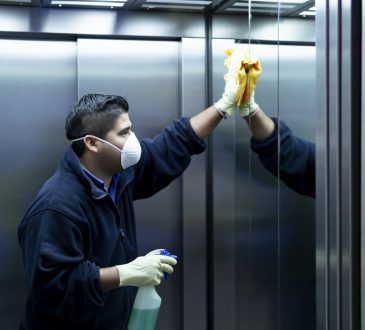 Male cleaner disinfecting elevator