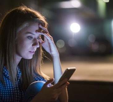 young woman looking at smart phone with worried expression