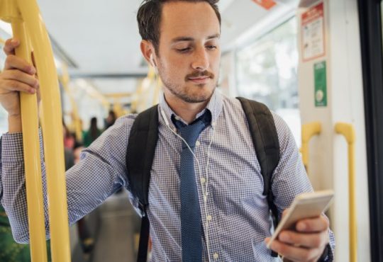 man looking at phone on bus