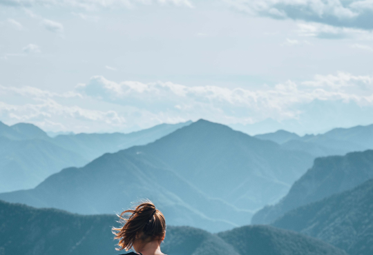 Woman sitting on mountain cliff