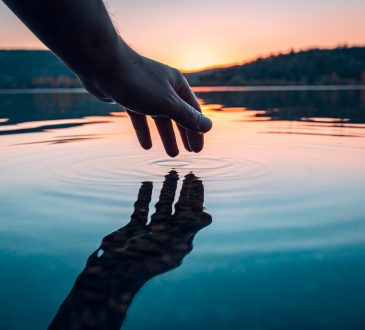 hand reflecting on surface of lake