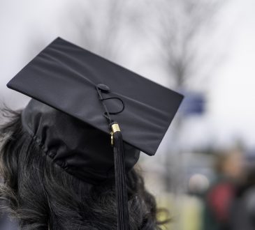 university student with long dark hair wearing mortarboard, from behind