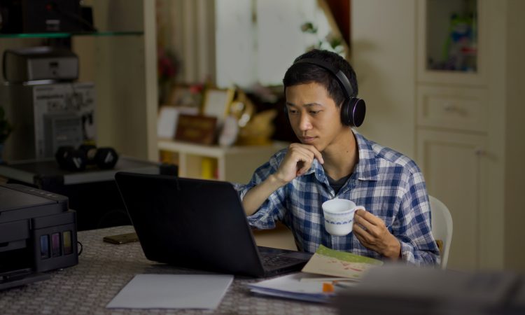 male student watching laptop drinking tea
