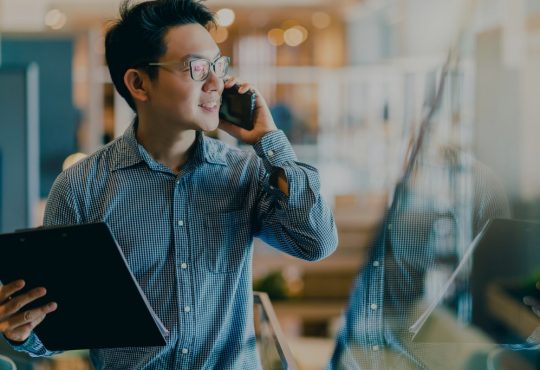 man holding clipboard and talking on cellphone in office
