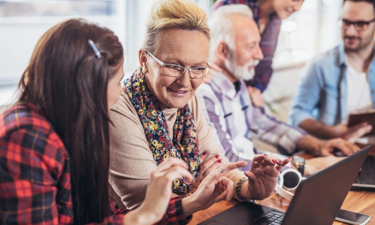 Young volunteers help senior people on the computer
