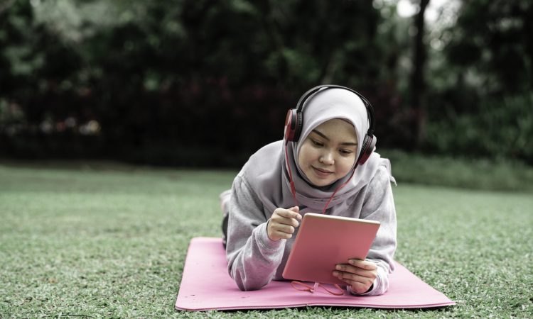 student lying on grass looking at tablet