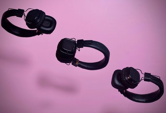 three pairs of headphones floating on diagonal line on purple backdrop