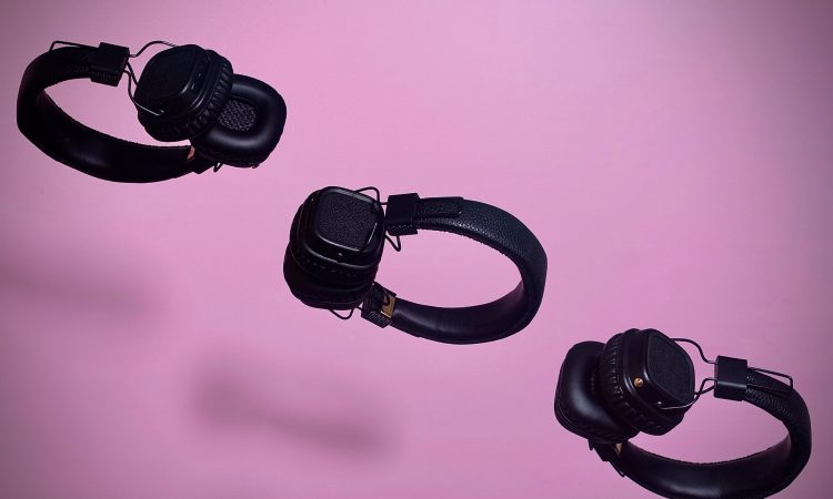 three pairs of headphones floating on diagonal line on purple backdrop