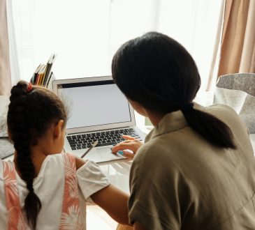 mom helping daughter with homework on laptop