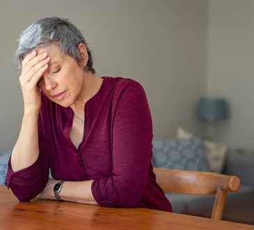 older woman looking stressed sitting at kitchen table