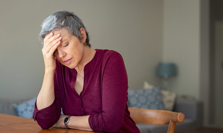 older woman looking stressed sitting at kitchen table