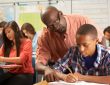 teacher helping pre-teen student in classroom
