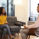 Woman Sitting On Couch Meeting With Male Counsellor In Office
