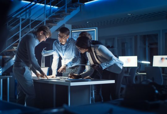 group of engineers working around table in office at night