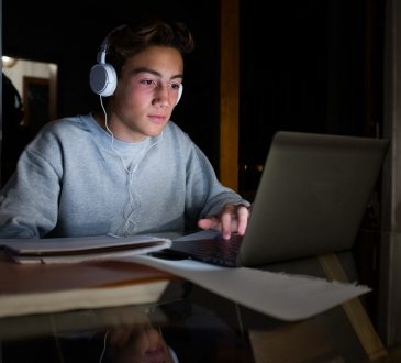 teen boy using laptop at night