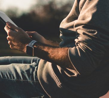 man sitting and reading ipad on bench