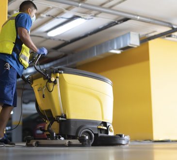 cleaning professional working in garage cleaning with sweeping machine