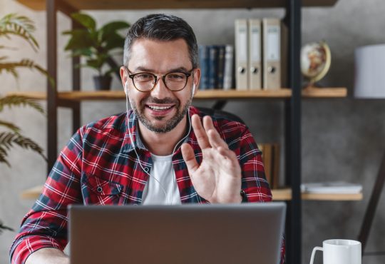 Middle aged man having video call from workplace at home