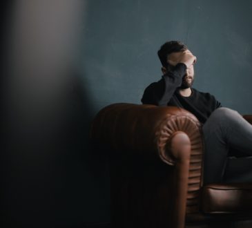 man sitting on couch looking depressed
