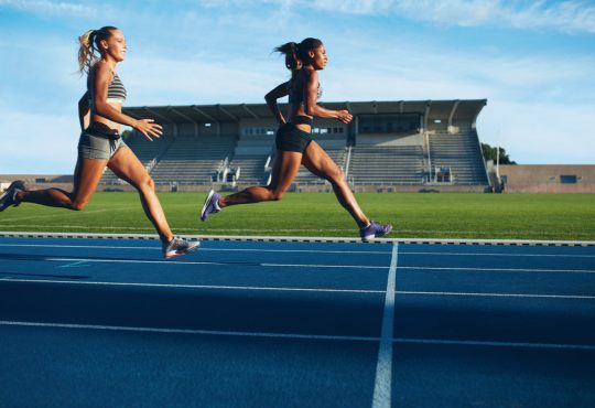 two women sprinting toward finish line on outdoor track