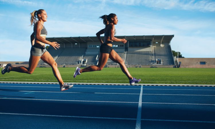 two women sprinting toward finish line on outdoor track