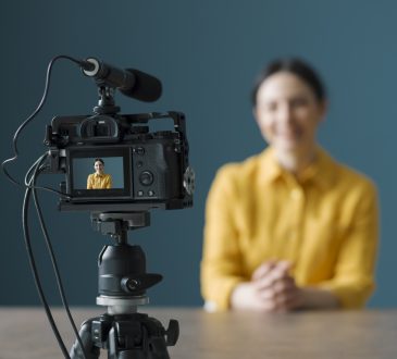 Smiling woman sitting in front of a camera and making a video blog