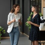 two women co-workers laughing and talking in office