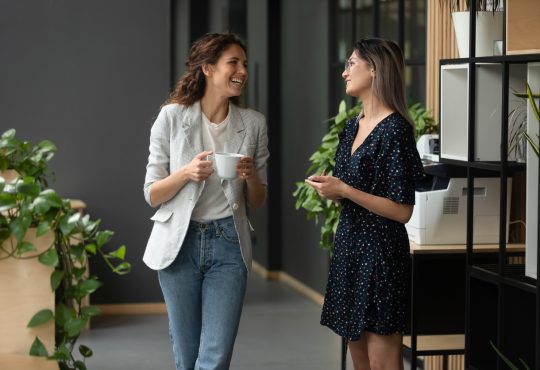 two women co-workers laughing and talking in office